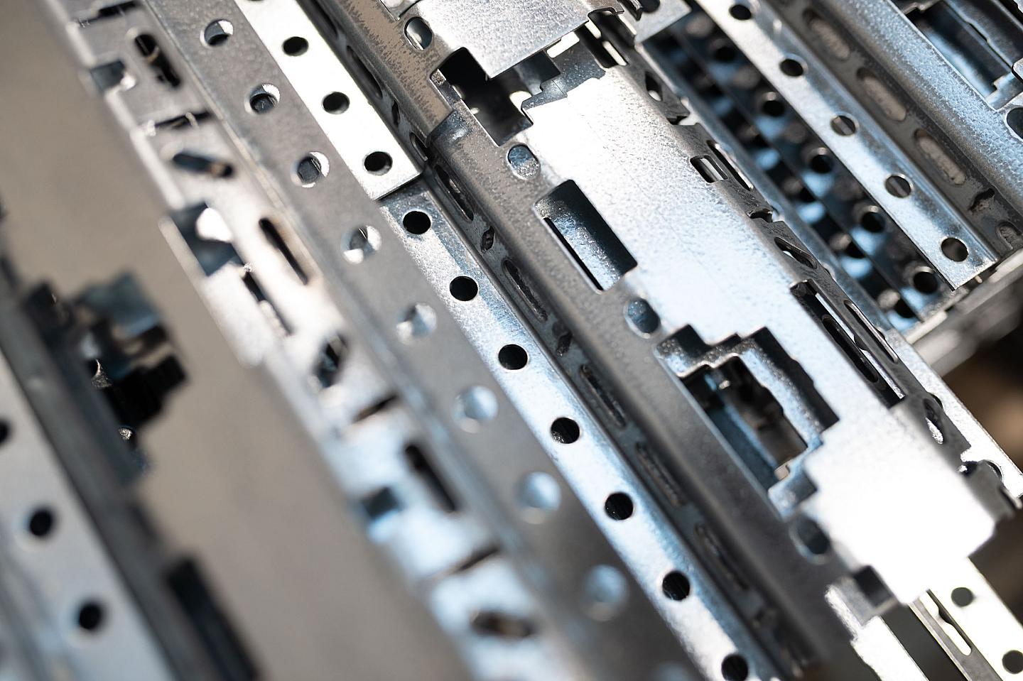 Nærbilde av metalliske metallrammer og deler som utgjør en datamaskins hovedkort, med mange hull og spor for komponenter.
