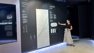 Kvinne som peker mot store informasjonstavler om materialer og design på en utstilling.