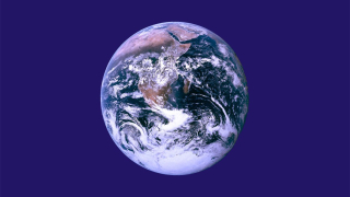 Jorden sett ovenfra med kloder, land, hav og skyer tydelig synlige mot en mørk blå bakgrunn.
