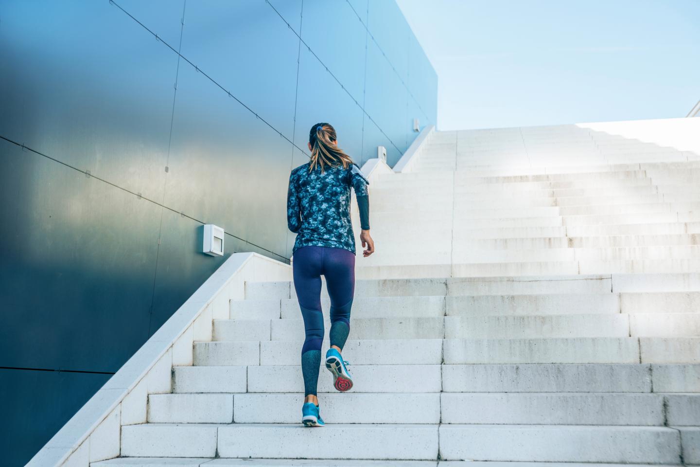 Dame som løper opp en trapp, ved siden av fasaden til en bygning